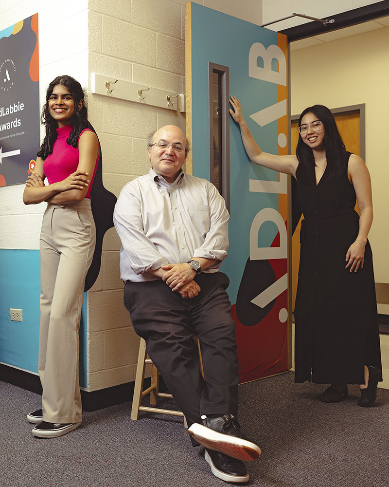 Two students and faculty advisor posing in the AdLab office.