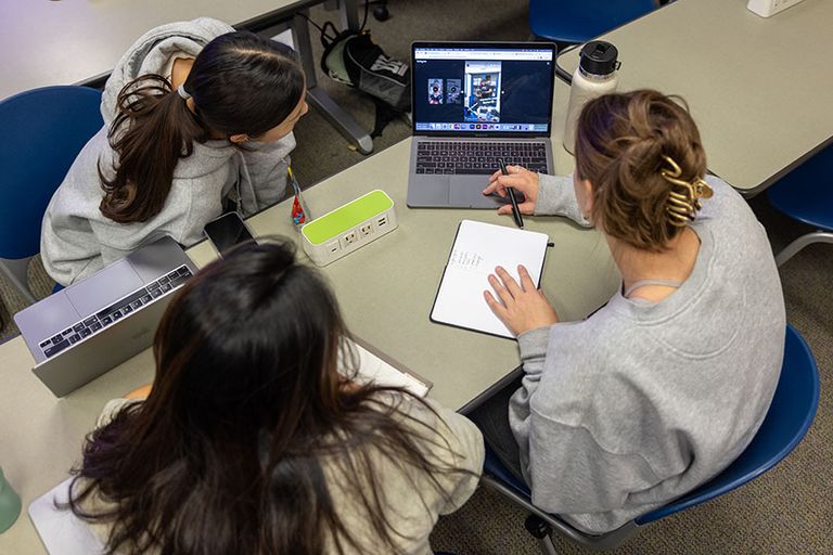 Looking down on a three-person team working at a laptop.