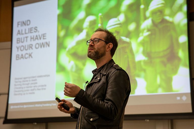 Man presenting in front of a screen.